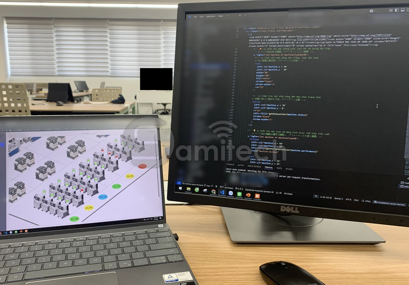 Bàn làm việc: laptop hiện mặt bằng 3D các máy với chấm trạng thái, màn hình lớn bên cạnh mở mã nguồn của chính giao diện đó.